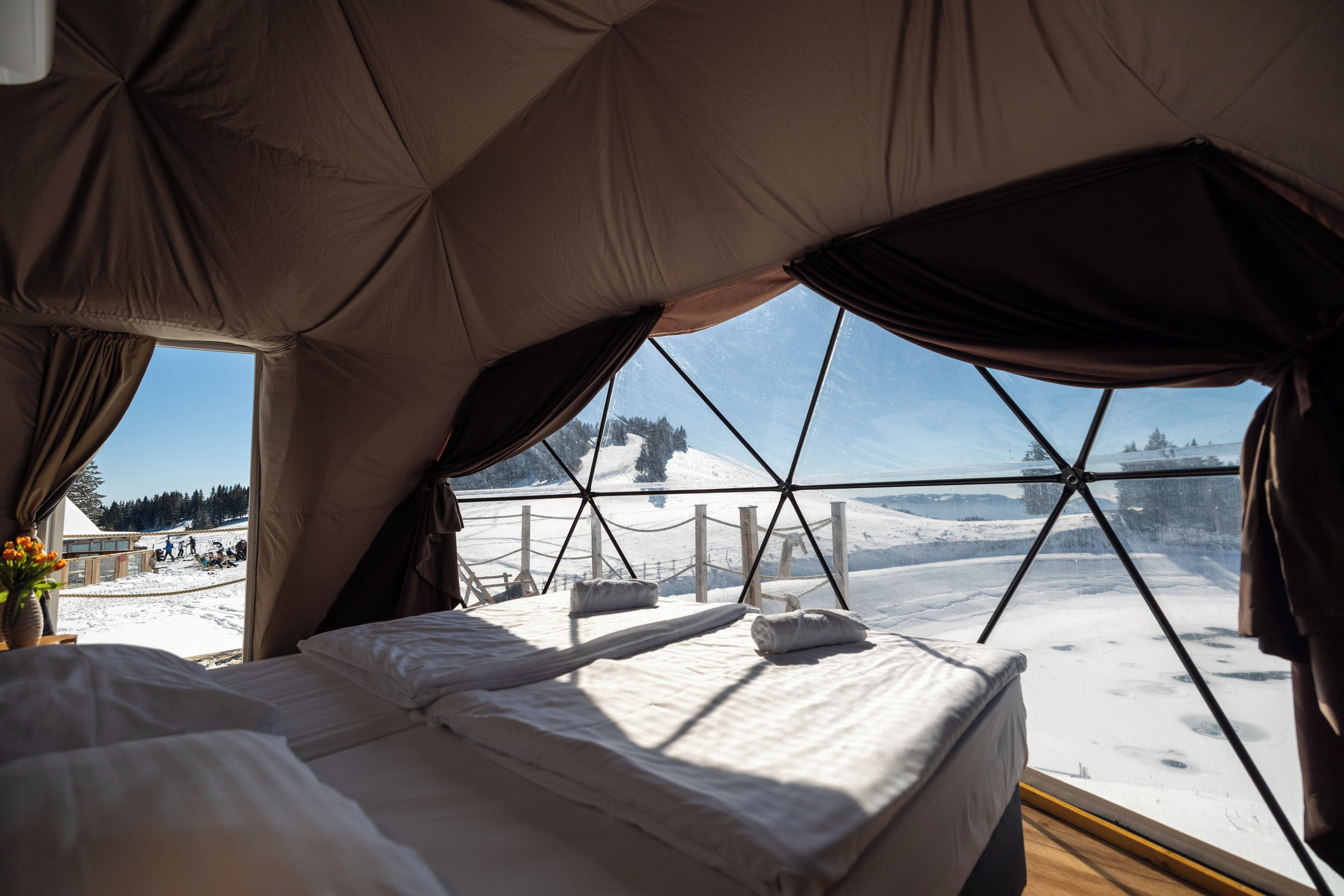 A tent with a bed and windows overlooking a snowy landscape.