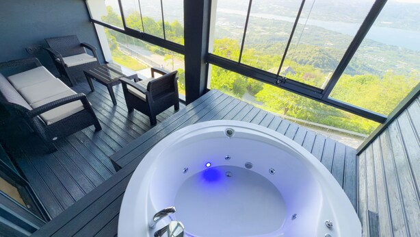 A hot tub with a view of a lake and forest. There is a seating area with chairs and a table. - adesa viev villas (Sapanca)