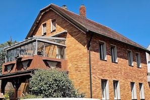 Ein zweistöckiges Backsteingebäude mit Balkon und großem Fenster.
