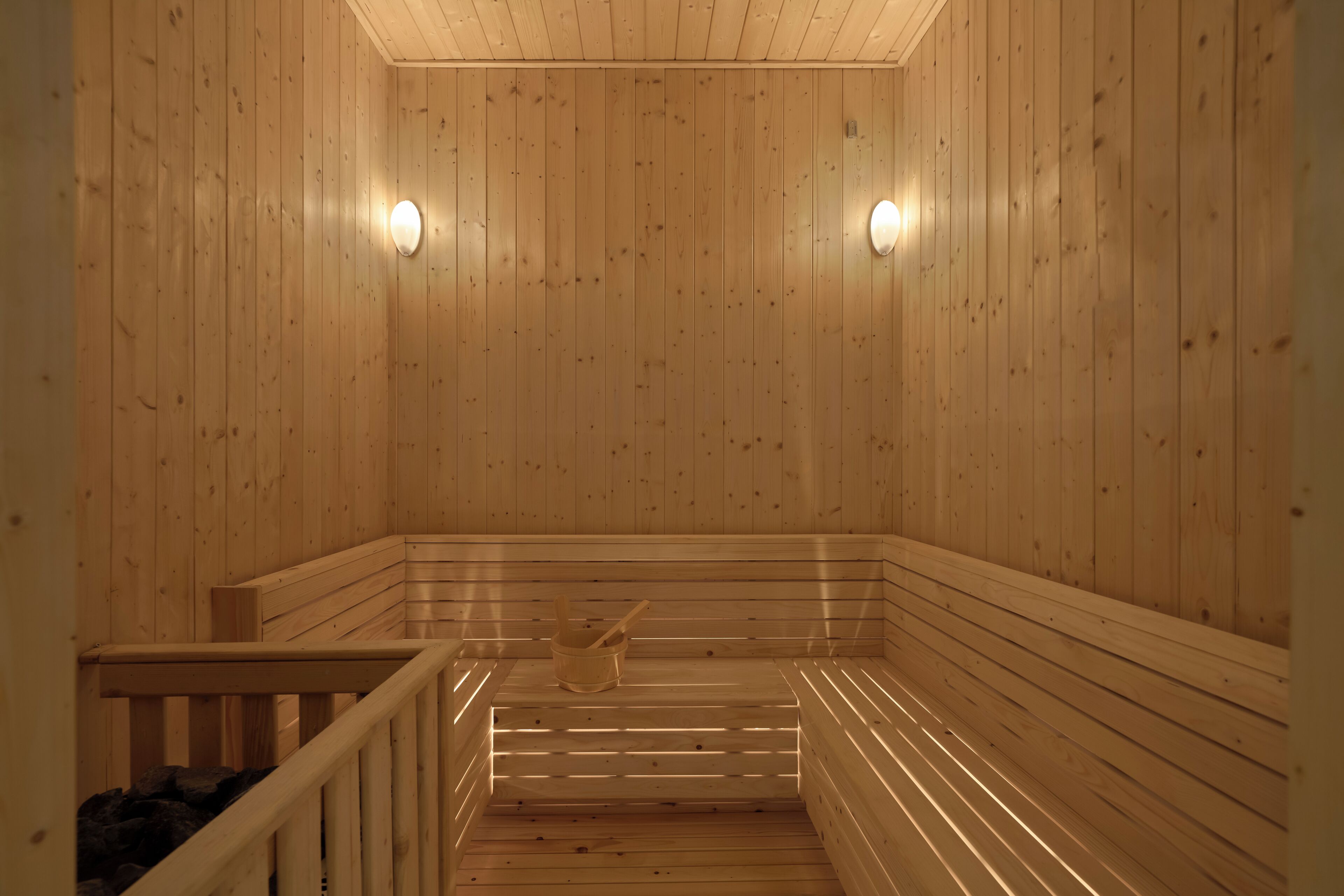 A wooden sauna with benches and a wooden bucket.