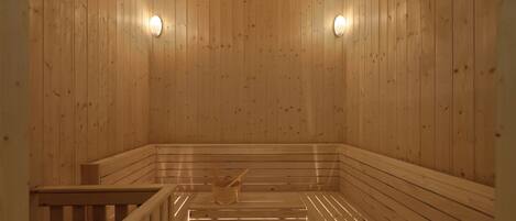 A wooden sauna with benches and a wooden bucket.