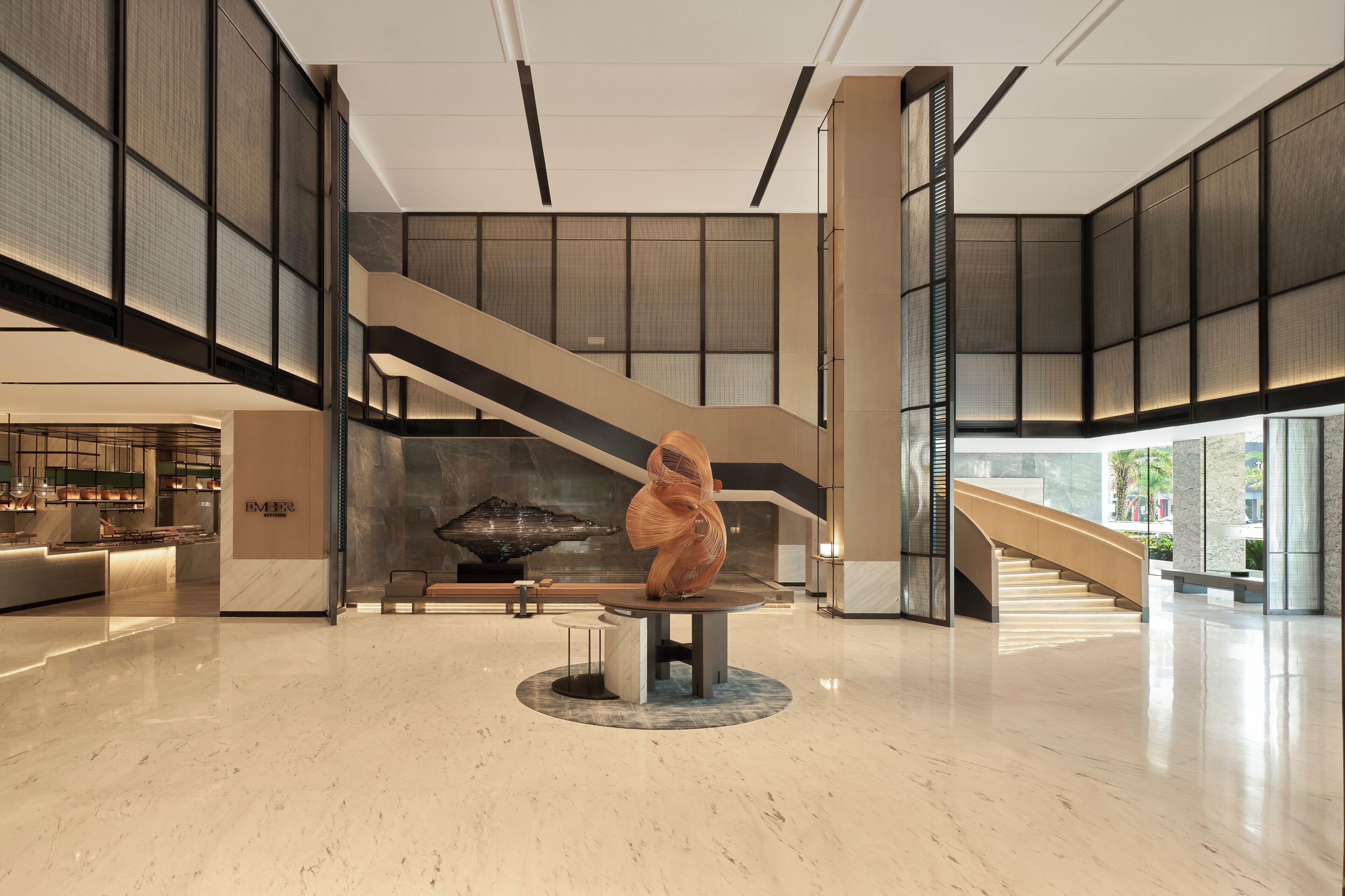 Un vestíbulo amplio con una escultura central, una escalera y una zona de estar.