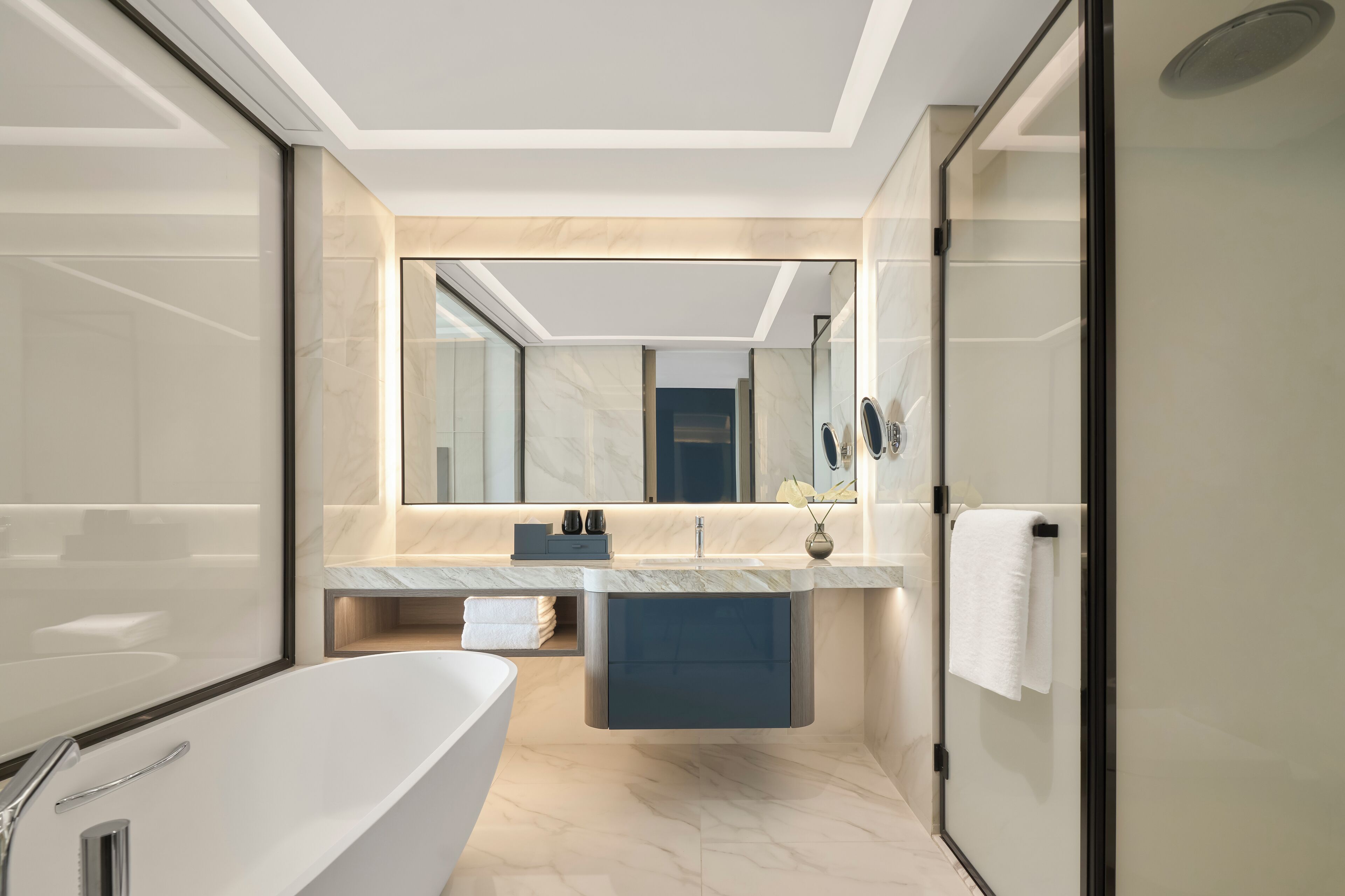 A modern bathroom with a freestanding bathtub, a vanity with a mirror, and a towel rack.