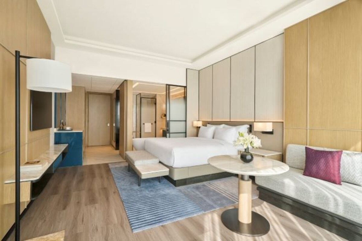 Une chambre d’hôtel moderne avec un grand lit, une table de chevet, une table ronde et un canapé.