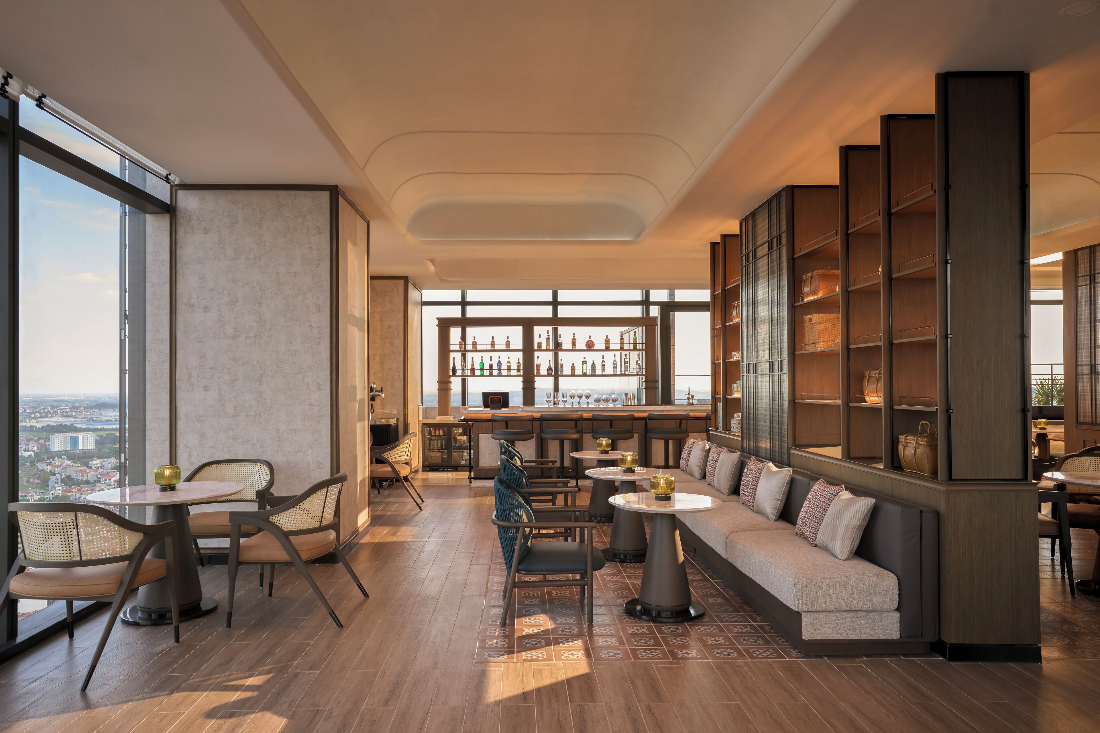 A modern lounge area with a sofa, chairs, a bar, and a large bookshelf.