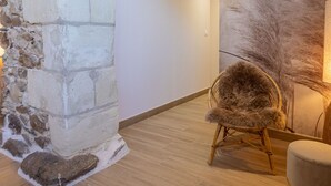 A room with a stone wall, a wooden floor, and a chair with a fur throw. - Spacious 8-bedroom cottage in Anjou vineyards (Blaison-Saint-Sulpice)