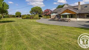 A property with a stone building, a grassy lawn, and picnic tables. - Spacious 8-bedroom cottage in Anjou vineyards (Blaison-Saint-Sulpice)