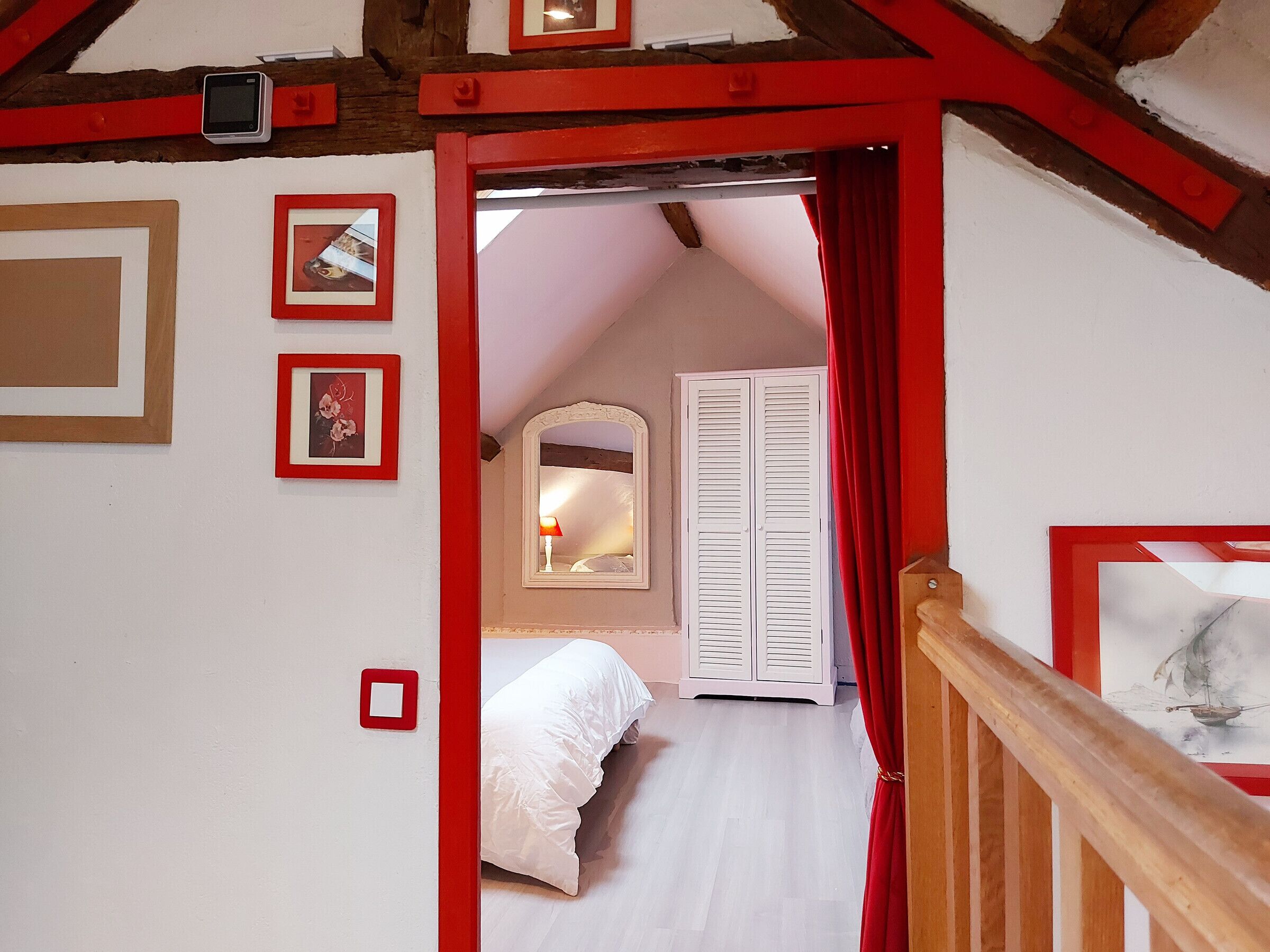 Une chambre avec un plafond en pente, un lit, une armoire et un miroir.