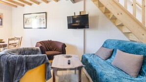 A cozy living room with a wooden staircase, a sofa, a chair, and a small table.