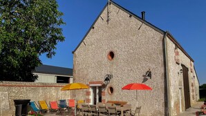 A building with a stone facade, outdoor seating area with tables and chairs, and potted plants. - La Grange: Comfortable Cottage in Briou, 5 Bedrooms (Briou)
