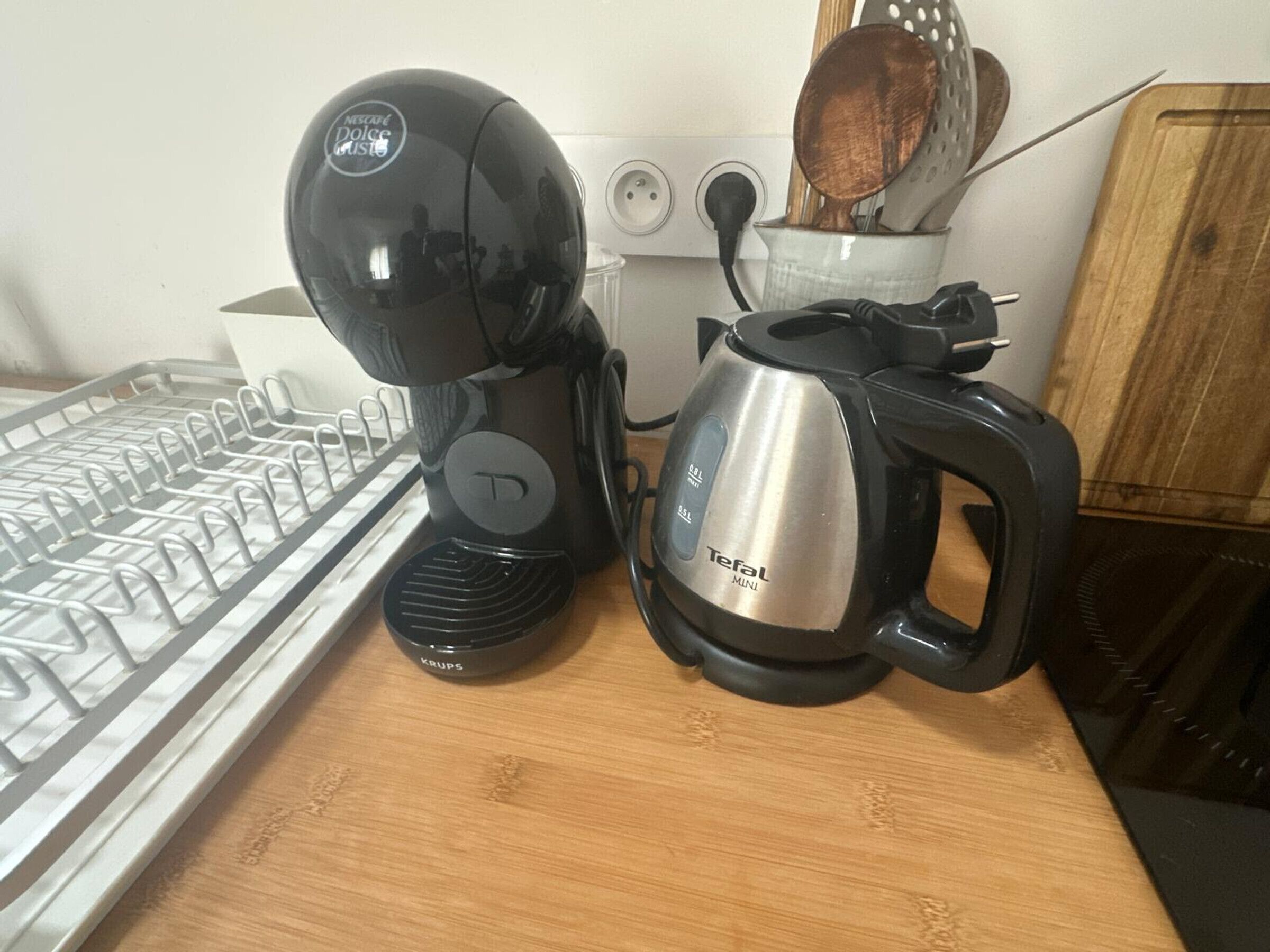 Un plan de travail de cuisine avec une machine à café, une bouilloire et un égouttoir à vaisselle.