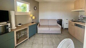 Un espace de vie compact comprenant un coin cuisine, un canapé, un téléviseur et un coin repas.