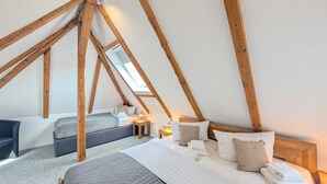 A cozy attic bedroom with a loft bed, a smaller bed, and a desk area. - Harzlodge Hilly – Your Private Family Holiday Apartment in the Harz Mountains (Braunlage)