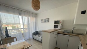 A compact kitchen with a dining area, a microwave, a sink, and a washing machine. - 2-star apartment near thermal baths with balcony (Balaruc-les-Bains)