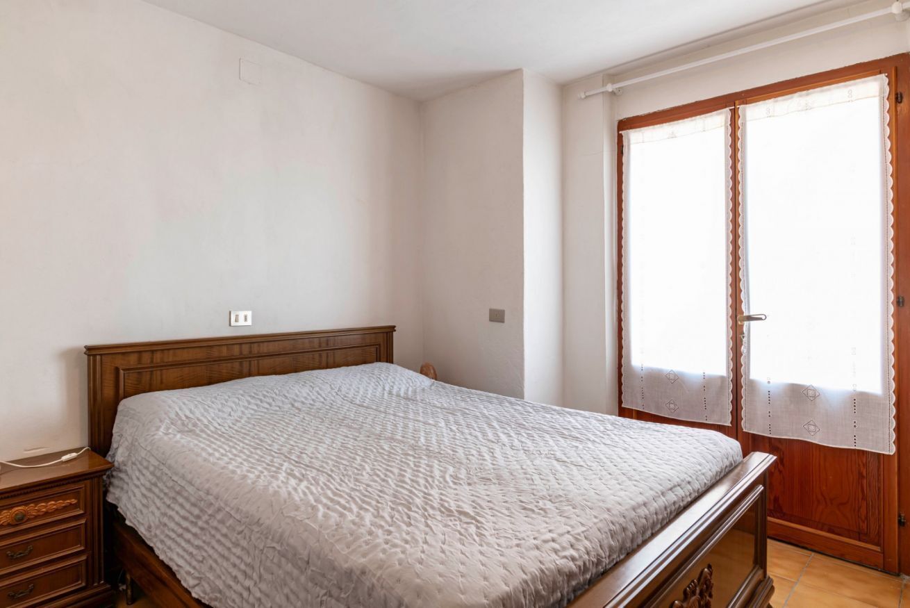 A bedroom with a wooden bed, a nightstand, and a window with curtains.