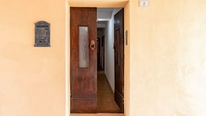 A hallway with a wooden door, a mailbox, and a number plate. - GuestHost - Battazzi House (Peglio)