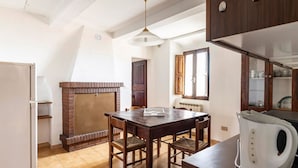 A kitchen with a wooden table, chairs, a brick fireplace, a white kettle, and wooden cabinets. - GuestHost - Battazzi House (Peglio)