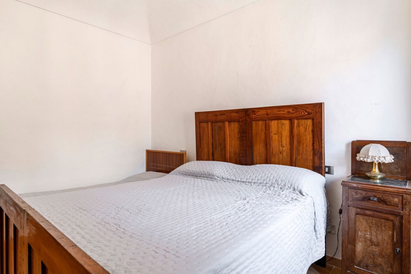 Un lit simple avec une tête de lit en bois, une table de chevet avec une lampe et une commode.