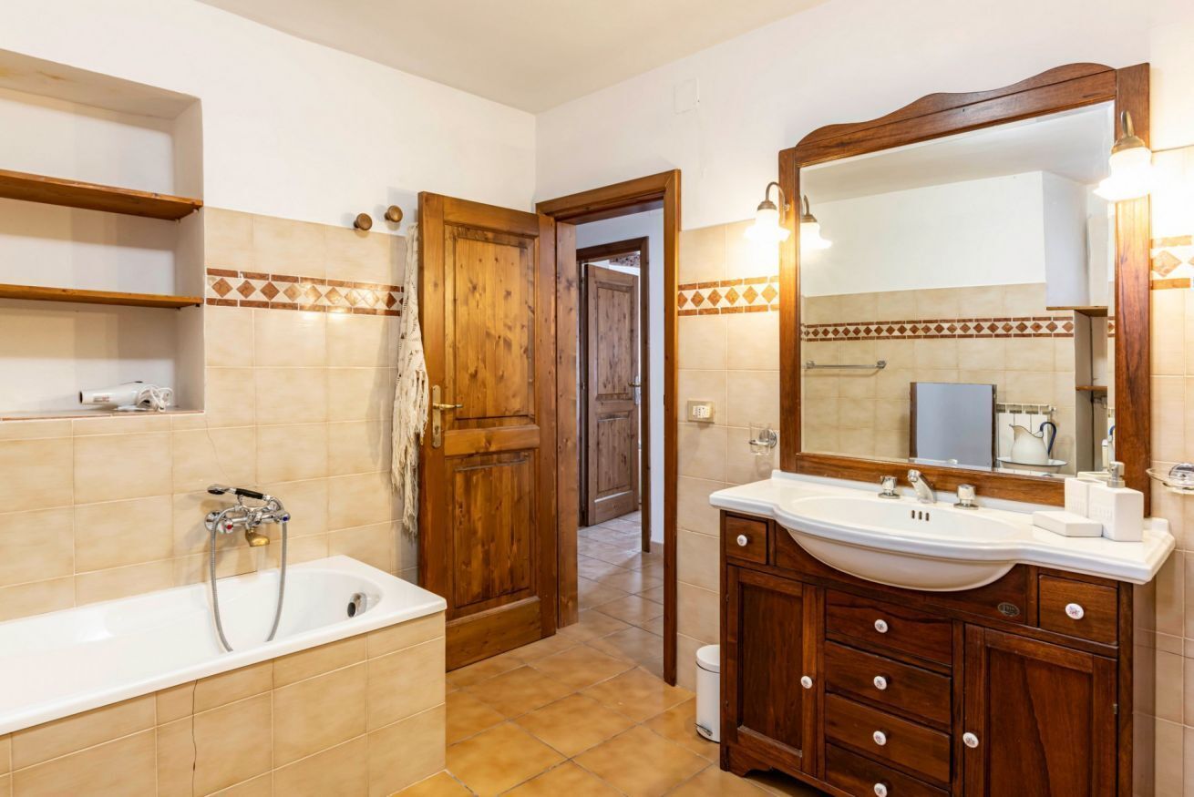 A bathroom with a bathtub, wooden vanity, and a large mirror.