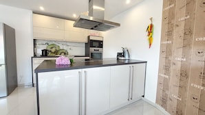 Cocina moderna con una isla central, horno empotrado y electrodomésticos de acero inoxidable.