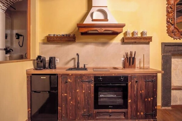 Una cocina con encimera de madera, horno empotrado y cafetera.
