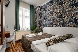 Habitación de hotel con cama, escritorio y ventana con cortinas.