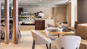 Um café moderno com balcão, área de estar e uma variedade de bebidas expostas.