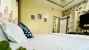 A hotel room with a bed, a television, and a wall with a floral pattern. - Green Edge Regency (Kolkata)