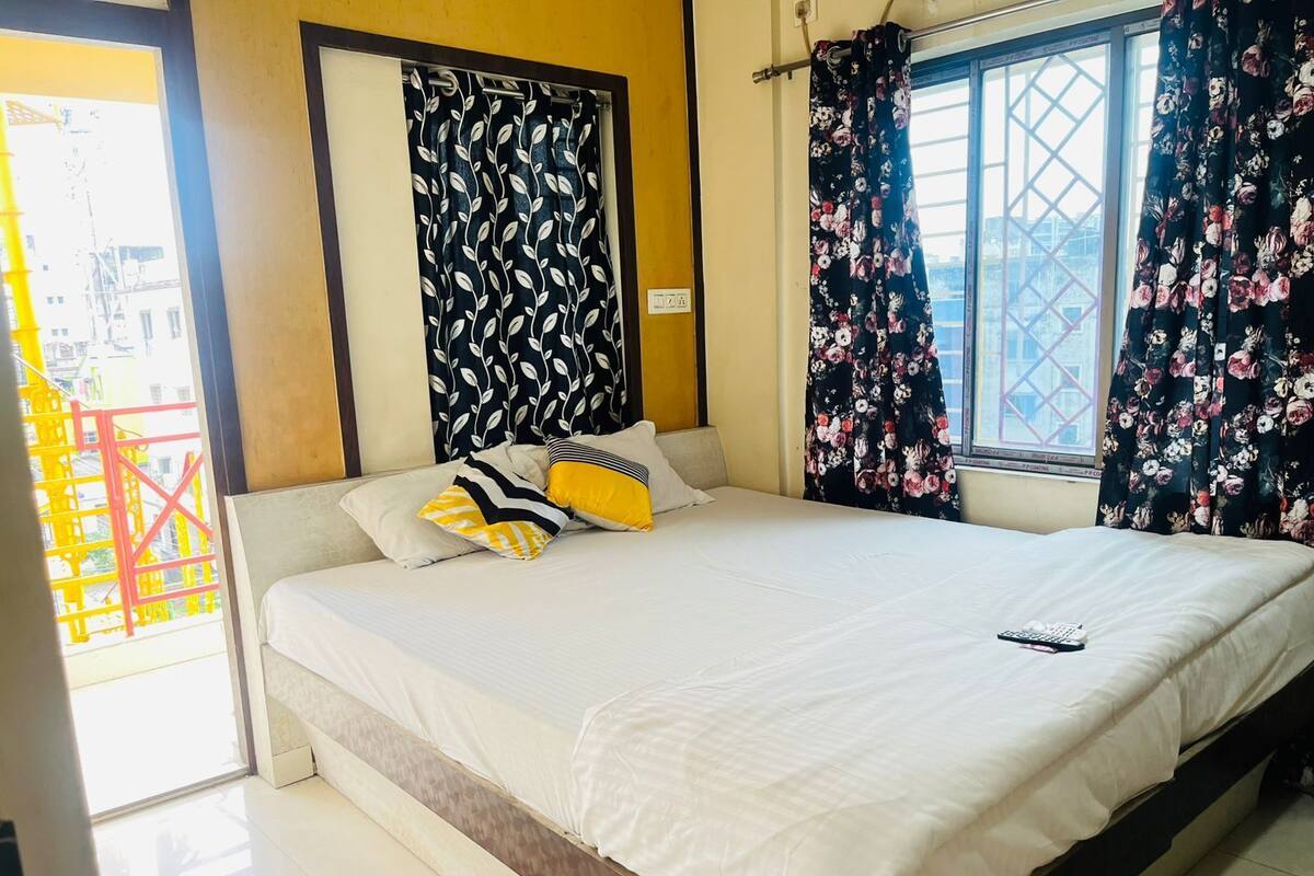 A bed with white bedding, a remote control, and decorative pillows.