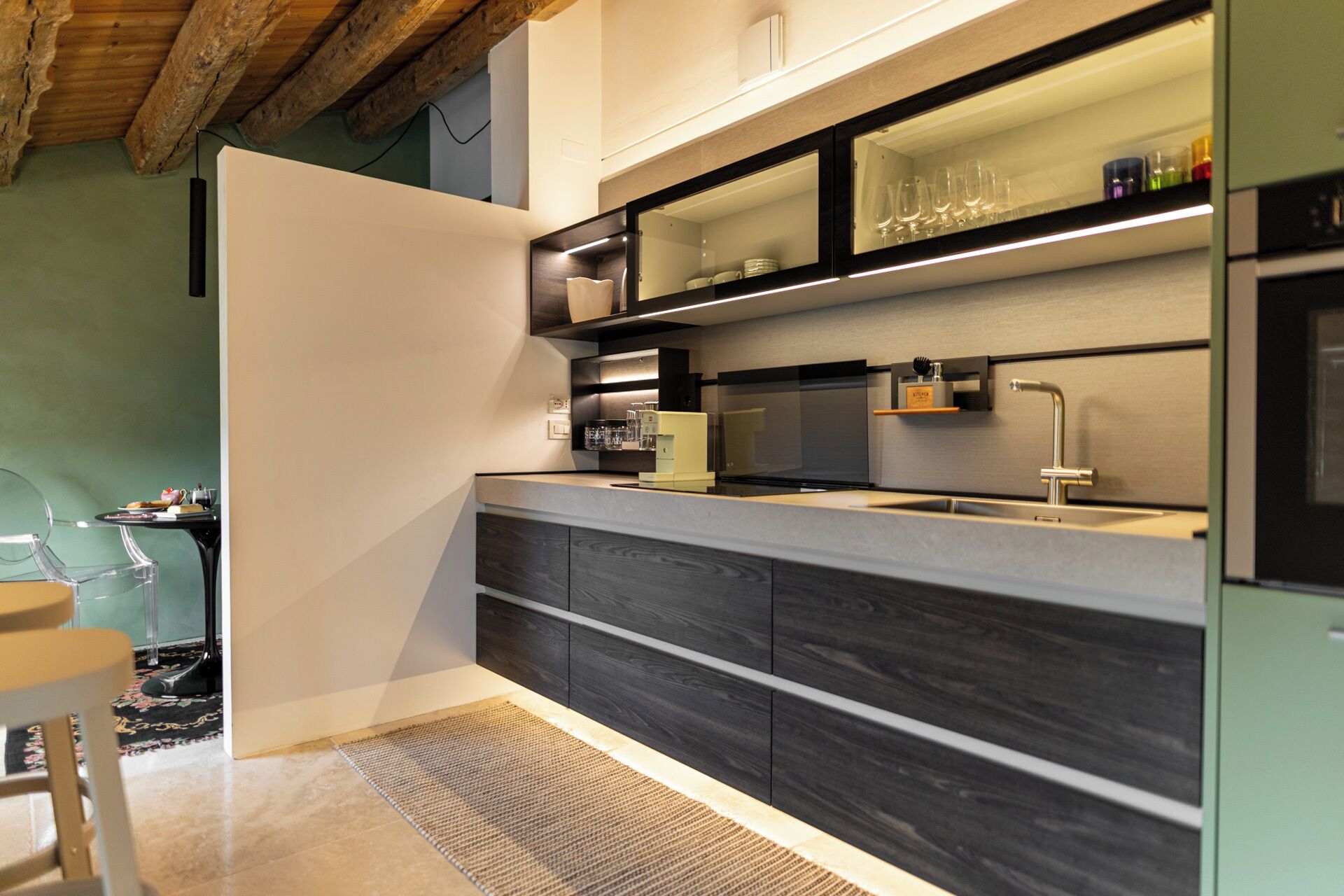 Una cucina moderna con mobili in legno scuro, un lavello in acciaio inossidabile e una dispensa per vini integrata.