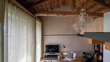 Una sala de estar moderna con techo de madera, un televisor grande, un sofá y un comedor.