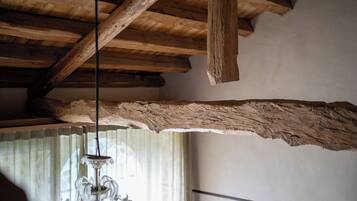 Techo de madera con vigas a la vista y una viga grande de textura rugosa colgando.