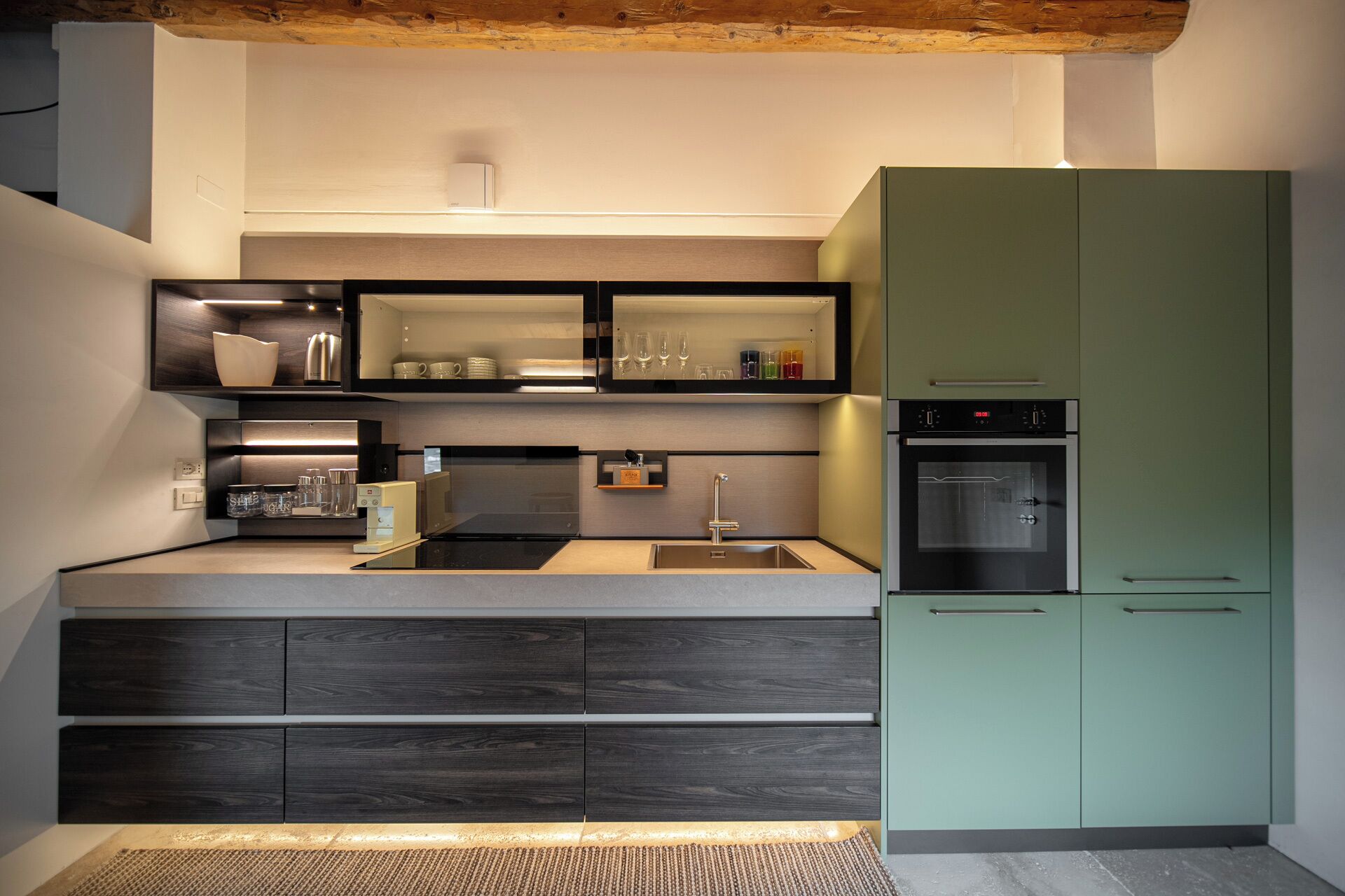 A modern kitchen with built-in appliances, a sink, and a green cabinet.