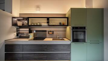 A modern kitchen with built-in appliances, a sink, and a green cabinet.