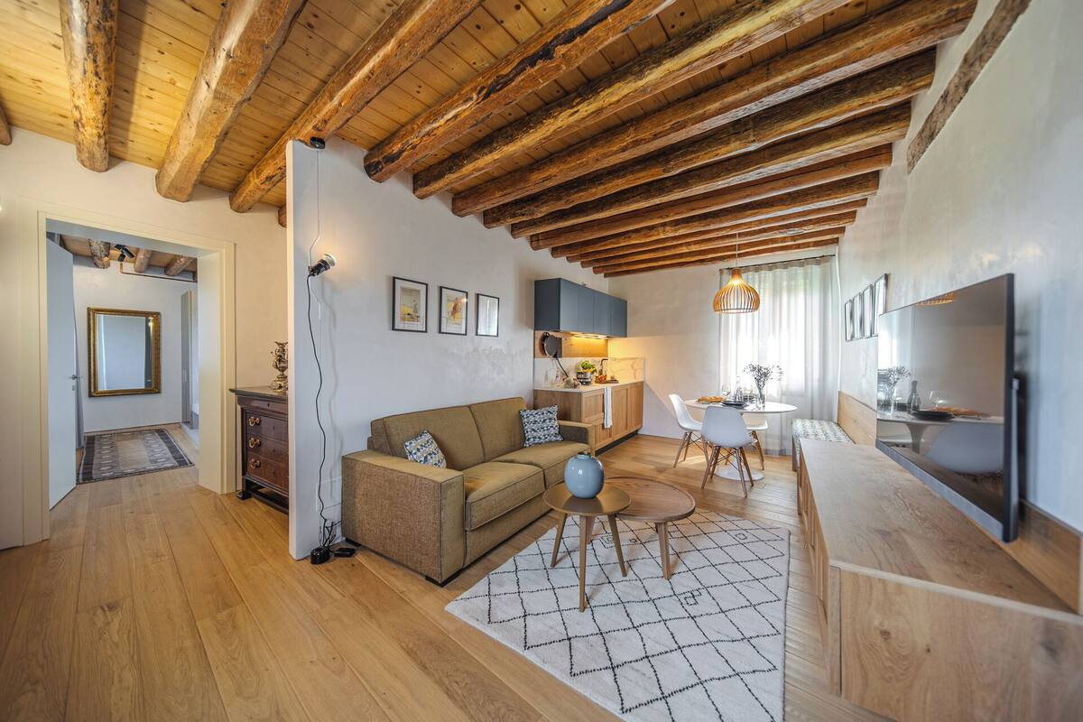 A cozy living room with a wooden ceiling, a sofa, a coffee table, and a dining area with a table and chairs.