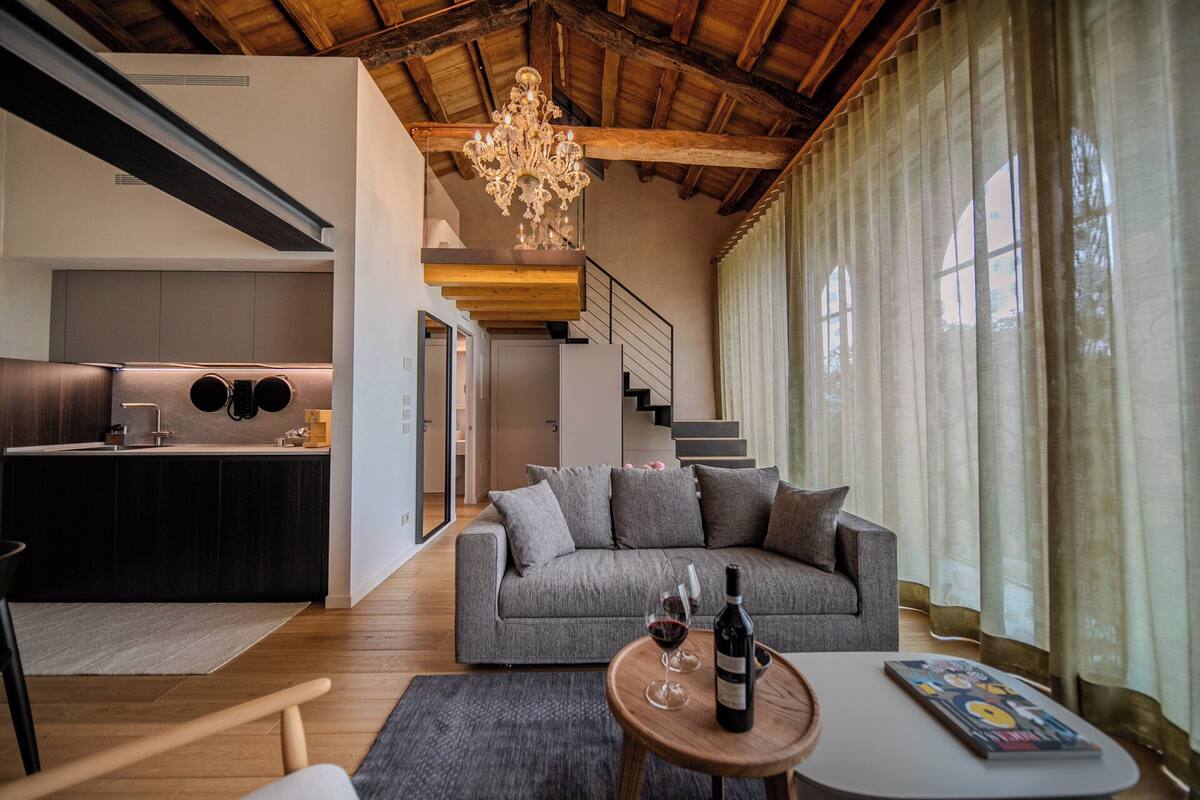A modern living room with a grey sofa, a wooden coffee table, and a wine bottle.
