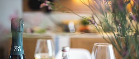 A bottle of Du Chi wine, a glass of white wine, and a vase with flowers on a table.