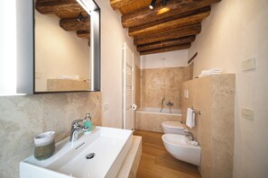 Een badkamer met een grote spiegel, een wastafel, een toilet met douchefunctie en een bad.