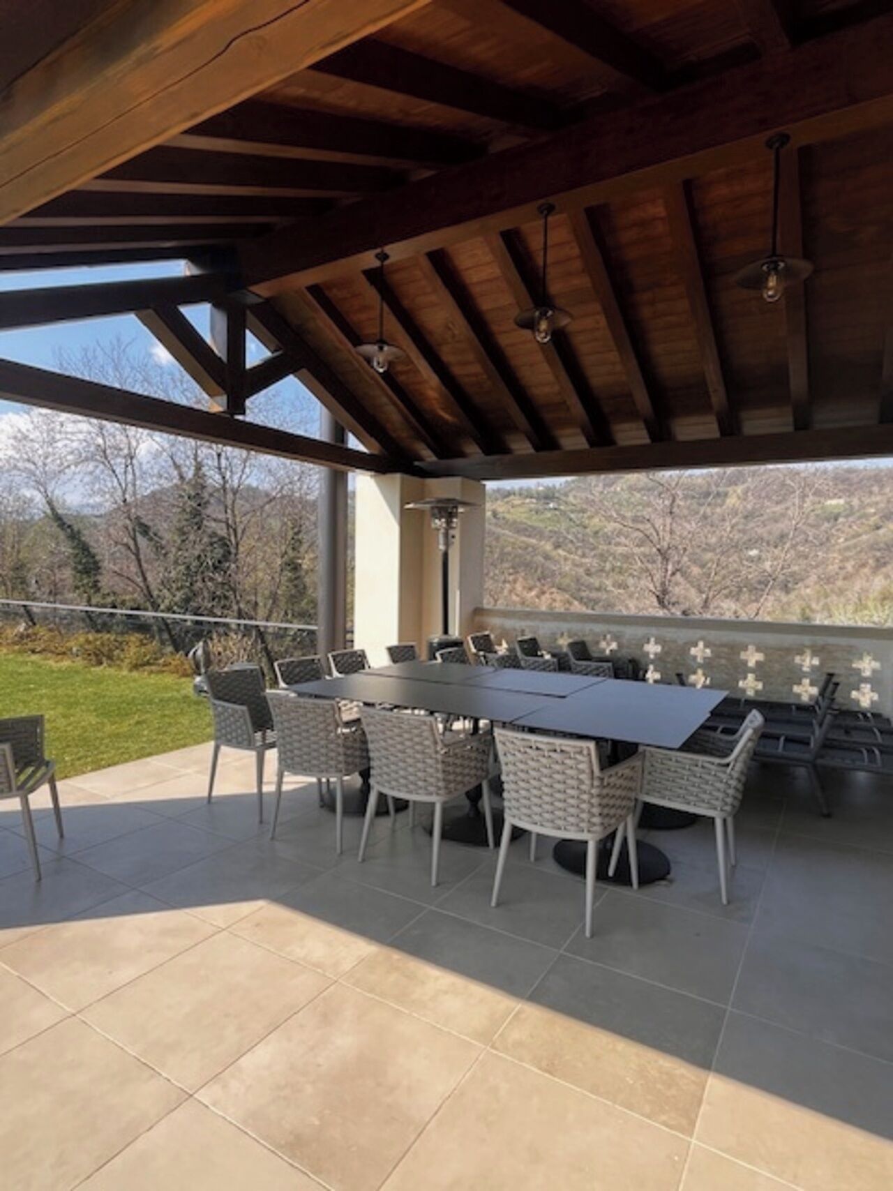 Een terras buiten met een tafel, stoelen, een pergola en uitzicht op het omliggende landschap.