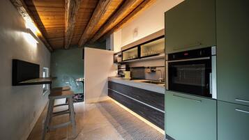 Una cocina moderna con techo de madera, horno empotrado y un mueble verde.