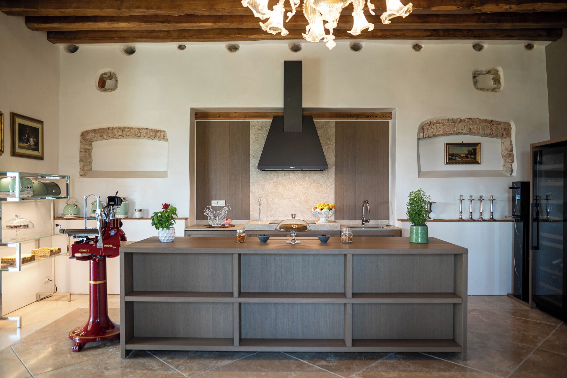 A modern kitchen with a central island, built-in appliances, and a rustic ceiling.