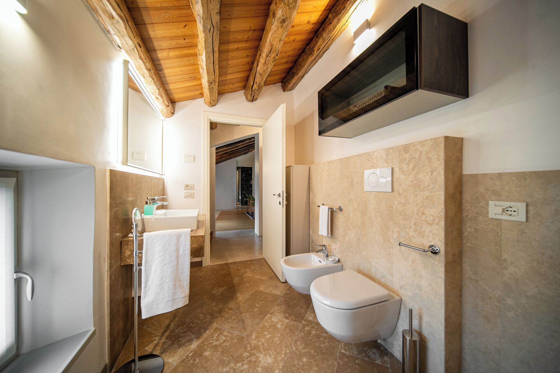Un baño moderno con bañera, dos inodoros, un bidé y un lavabo con espejo.