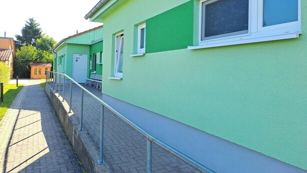 A green building with a covered walkway, a door labeled "House 4", and a window. - Cozy bungalow in the heart of the Eichsfeld (Uder)