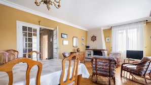 A dining area with a table and chairs, a television, and a fireplace. - Holiday Home 'Maison De Caractère' with Shared Terrace, Private Garden and Wi-Fi (Cancale)