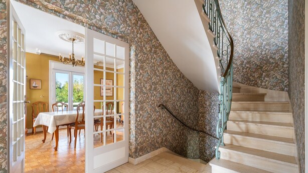 A staircase with a floral wallpaper, a dining area with a table and chairs, and a chandelier. - Holiday Home 'Maison De Caractère' with Shared Terrace, Private Garden and Wi-Fi (Cancale)