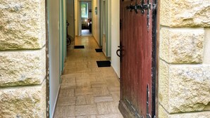 A stone-walled hallway with a wooden door, leading to a room with a view of a green landscape. - Ker Aloueder, sleeps 10, beach access, panoramic sea view (Santec)