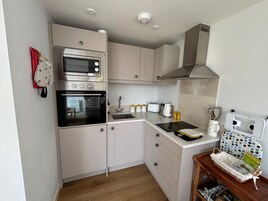 Uma cozinha compacta com micro-ondas, forno, pia e um pequeno espaço de refeições com mesa e cadeiras.
