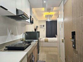 Una habitación de hotel compacta con kitchenette, cama, ducha y baño.