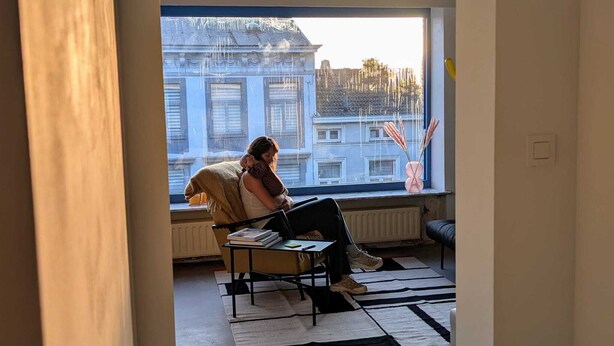Huoneessa on suuri ikkuna, patteri, mustavalkoinen matto ja tuoli.