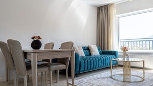 Una sala moderna con un sofá color turquesa, una mesa de comedor con sillas y una mesita redonda con un florero.